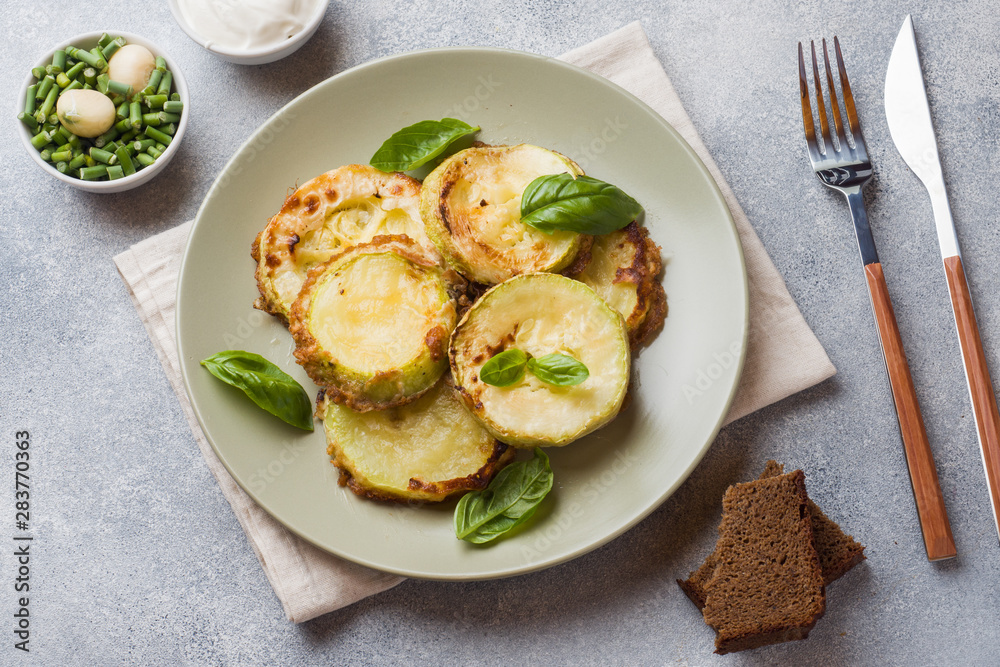 Slices of fried zucchini in batter with garlic and Basil on a plate.