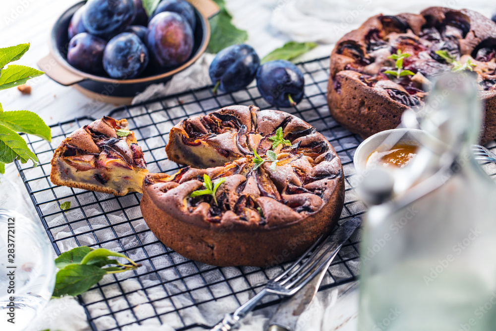 Delicious sweet pies with plums on white table, close-up Delicious sweet pies with plums on white table, close-up