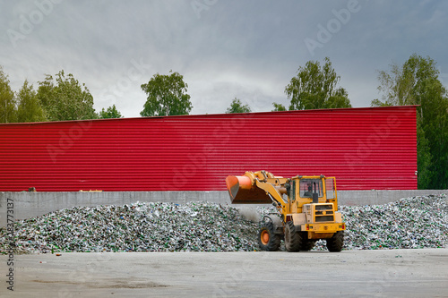 Front loader working at yard of sorting cullet. Recycle cullet at yard of processing plant. Recycling and reuse industry, warehouse. Gathering broken glass and bottles at the sorting station photo
