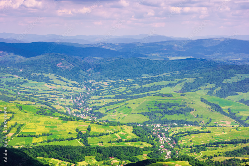 view from a mountain top in to the green valley. beautiful summer landscape of bilasovytsya village, volovets district, transcarpathia region, ukraine. gorgany ridge in the distance