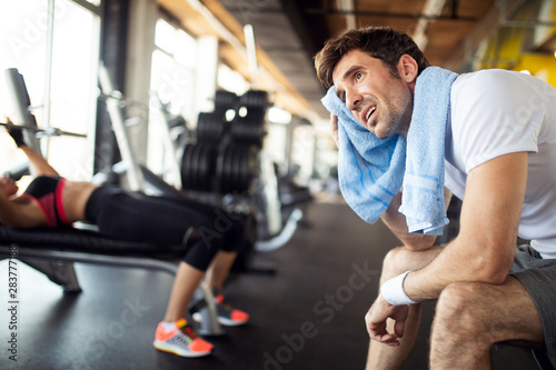 Sweaty after great work out. Handsome young men in sportswear whipping sweat with towel