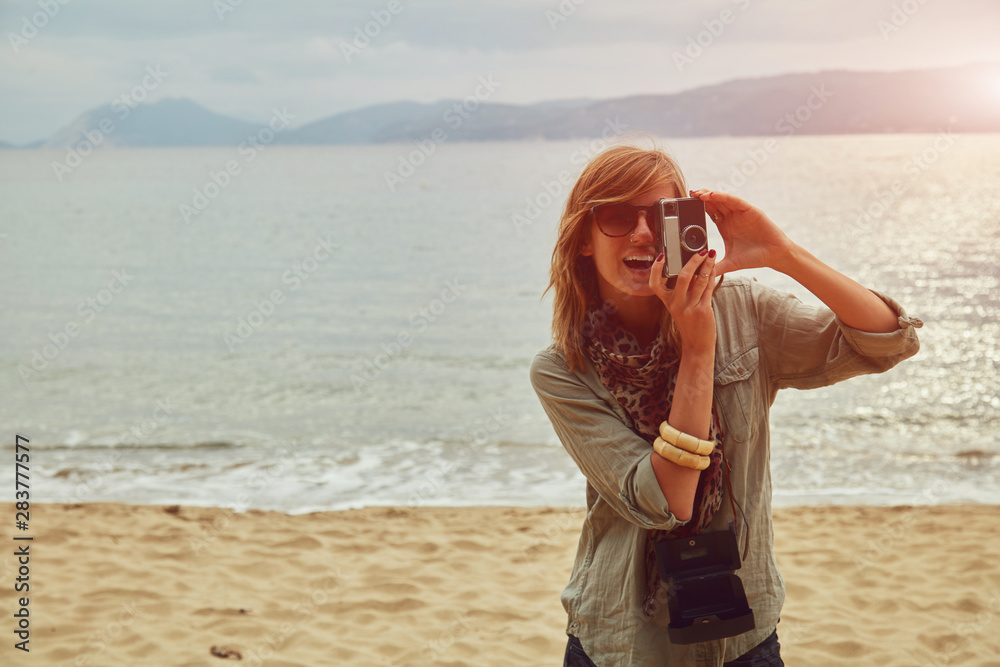 Fashionable woman holding camera on the beach. Fashionable woman holding camera on the beach.