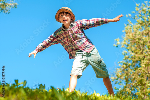 Active boy with arms outstretched against a blue sky having fun. Happy summer. Vacation