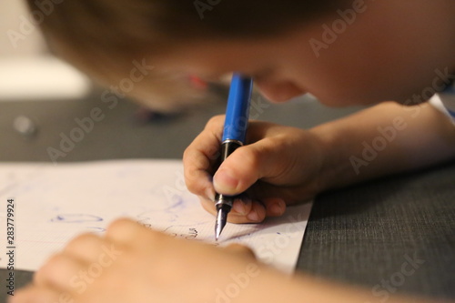 Jeune enfant qui apprend à écrire avec un stylo plume photo