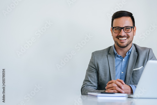 Portrait of young smiling cheerful businessman in office looking at camera copy space