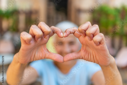 Cute senior old woman making a heart shape with her hands and fingers. Perfect  nice  aged  old  pretty woman  lover in t-shirt making  showing heart figure with fingers  looking at camera