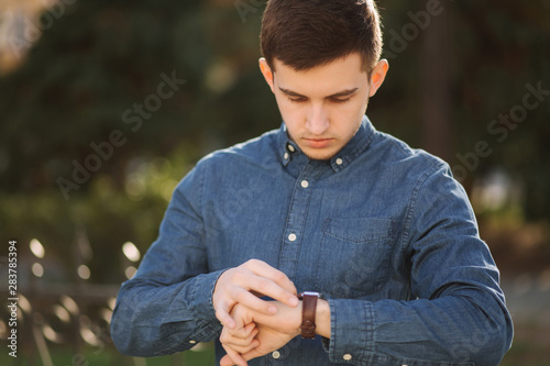 Handsome business man look at the watch in the city. Man ajust the exact time on the watch photo