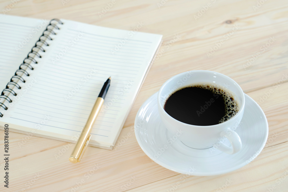Notebook pen and cup of coffee in wood table