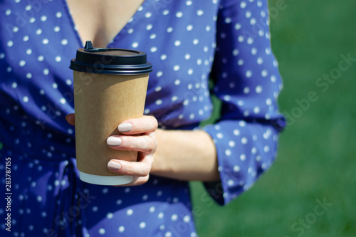 Craft Cup of coffee in the hands of the girl. The grass on the back of the dress.