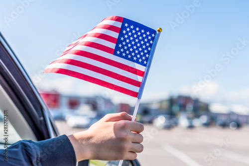 Boy holding Flag of America from the open car window on the parking of the shopping mall. USA.Concept