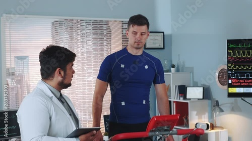 Multiracial doctor telling athlete about something during stress testing in sports lab with scyscrapers in the background. In Scientific Sports Laboratory. photo