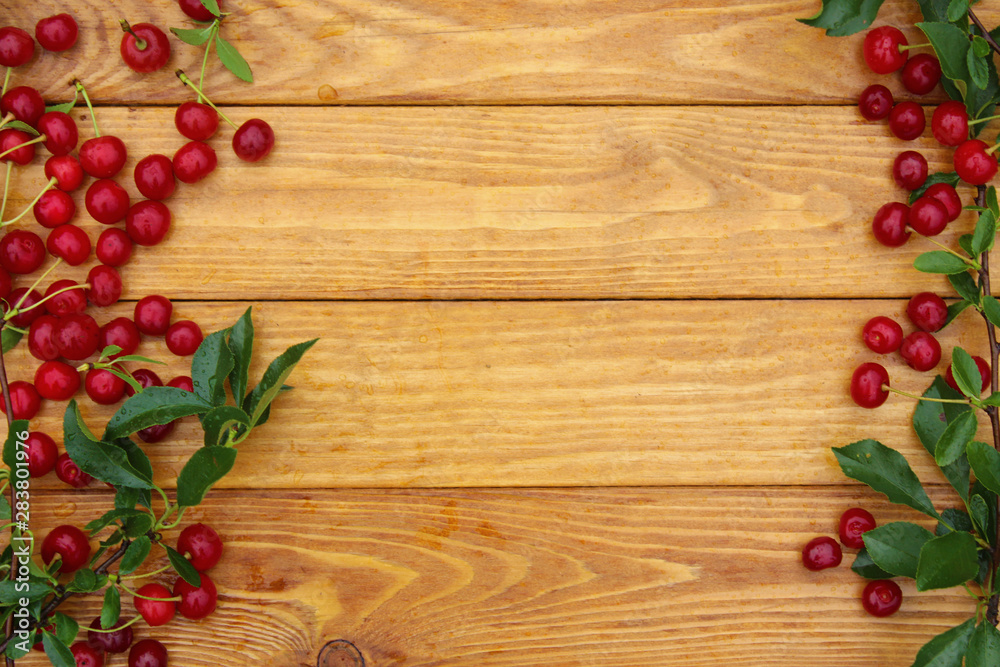 Fresh cherries with leaves on a wooden background Fresh cherries with leaves on a wooden background