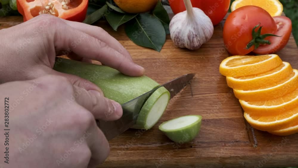 Person hands cutting zucchini on cutting wooden board. Person hands cutting zucchini on cutting wooden board.