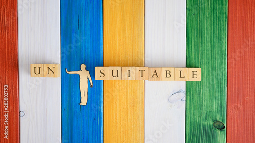 Paper cut silhouette of a man pushing away letters Un from the word Unsuitable