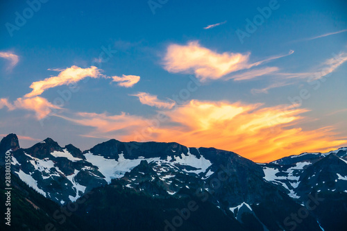 Alpenglow on clouds over a rugged mountain range in Mt. Rainier National Park. © Don Landwehrle