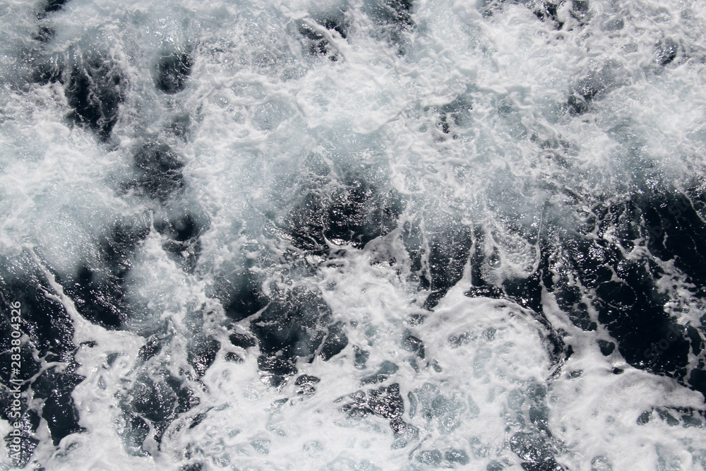 Obraz premium Background of the sea. Sea, ocean, wave. Beautiful view of the bubbling and splashing sea water and foam in the blue sea.