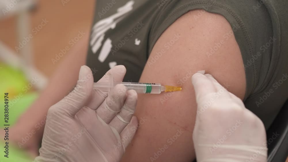 Doctor doing injection in hospital room and putting plaster on the patients arm after injection. healthcare concept