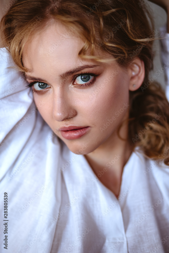 Young blonde woman in a casual white shirt and jeans in a loft interior, close up fashion portrait Young blonde woman in a casual white shirt and jeans in a loft interior, close up fashion portrait