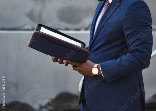 Midsection of man in suit holding notebook