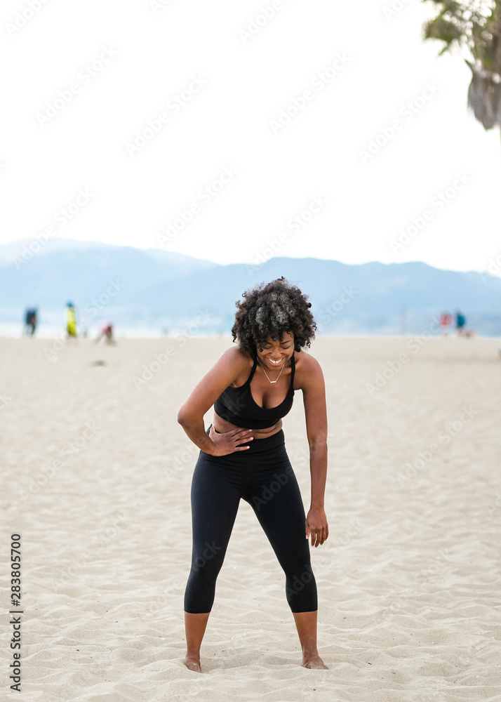 Woman bent over laughing on beach Woman bent over laughing on beach