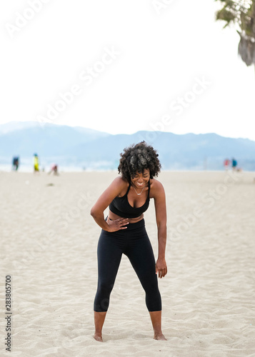 Woman bent over laughing on beach