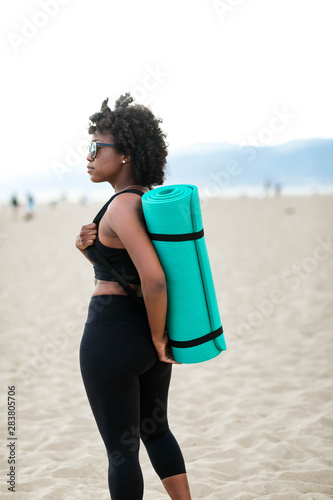 Profile of woman carrying yoga mat on beach