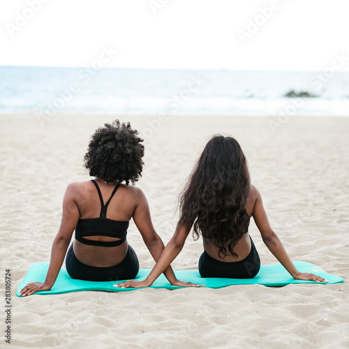 Rear view of two women sitting on beach towel