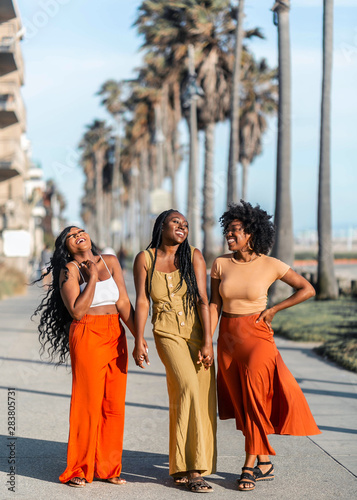 Women on sidewalk holding hands and laughing