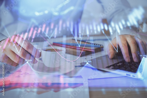 Forex graph with businessman working on computer in office on background. Concept of hardworking. Double exposure.