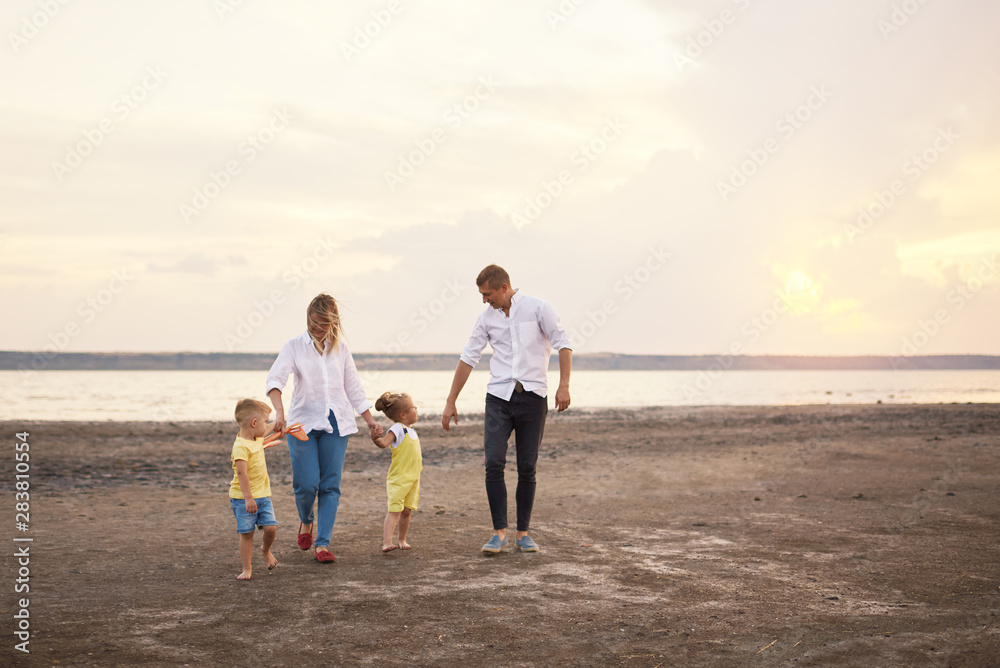Happy family playing with toy airplane on the beach on sunset. Dreams of being a child