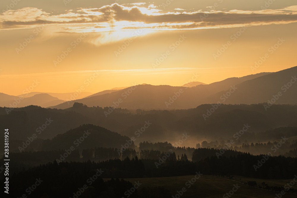 Hilly landscape during warm and bright sunrise. Very peaceful and pleasing scene. Forests and hills without any industry or buildings.