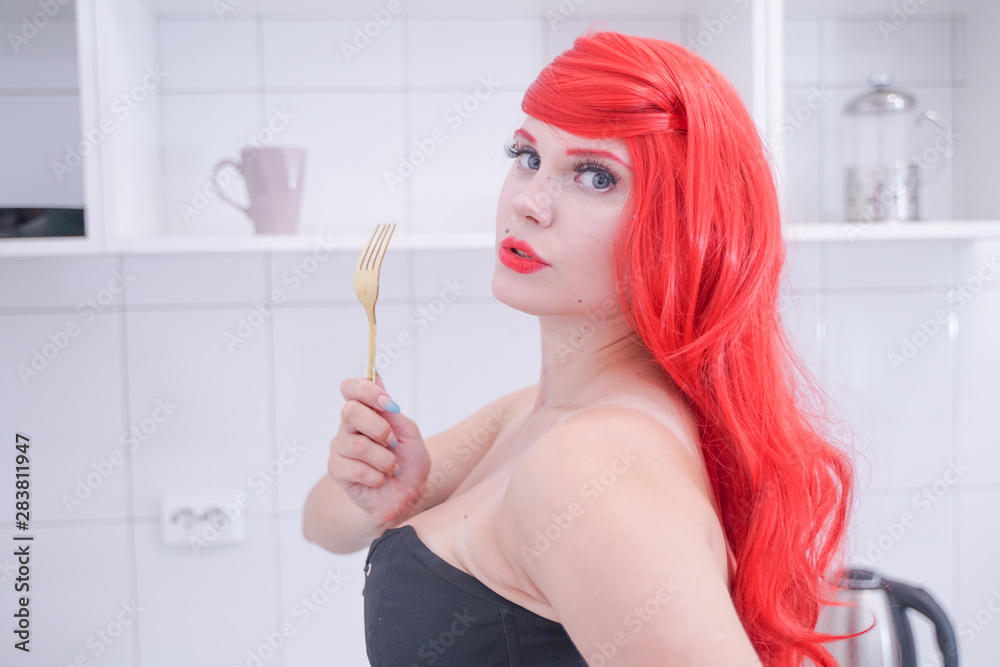 girl in black corset with red hair holding fork in white kitchen girl in black corset with red hair holding fork in white kitchen
