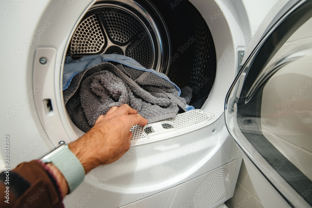 Man hand arranging clothes towels in the modern drying machines hose Man hand arranging clothes towels in the modern drying machines hose