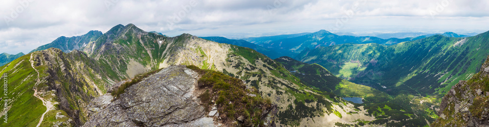 Panoramic view from Placlive peak on Western Tatra mountains or Rohace panorama. Sharp green mountains and lake rohacske pleso, ostry rohac, hruba kopa and volovec with hiking trail on ridge. Summer