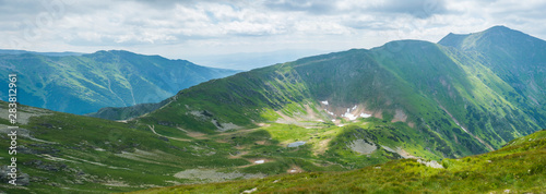 Panoramic view from Placlive peak on Western Tatra mountains or Rohace panorama. Sharp green mountains and lake rohacske pleso  ostry rohac  hruba kopa and volovec with hiking trail on ridge. Summer