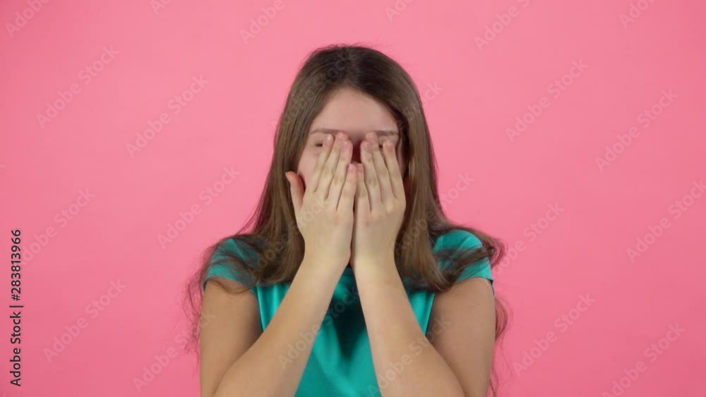 Girl is scared and hiding her face in studio on pink background. Slow motion Girl is scared and hiding her face in studio on pink background. Slow motion