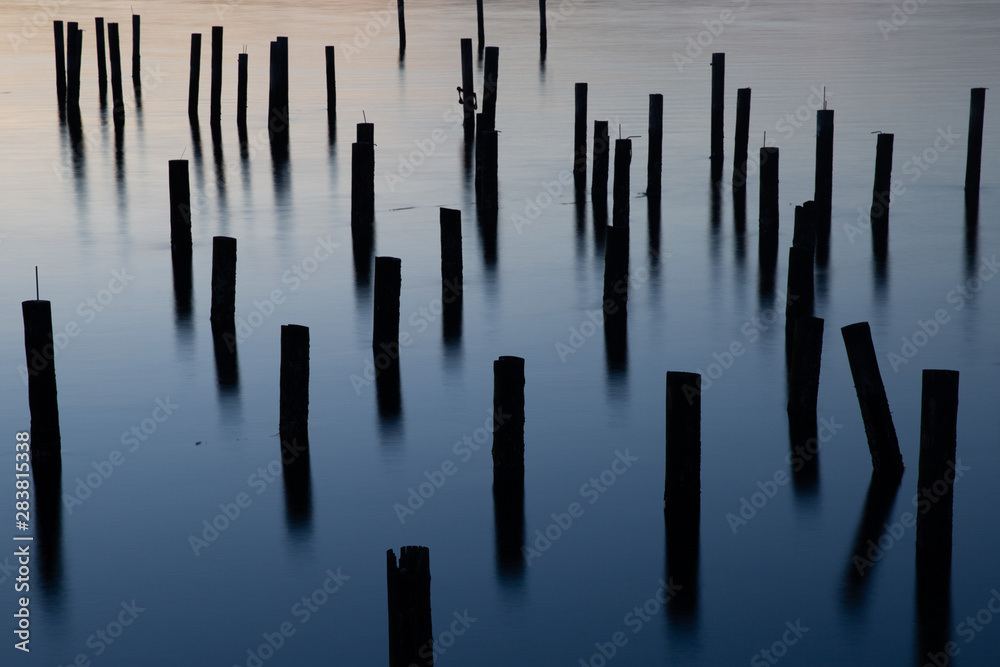 long exposure of wood pilings in blue ocean water at dusk long exposure of wood pilings in blue ocean water at dusk