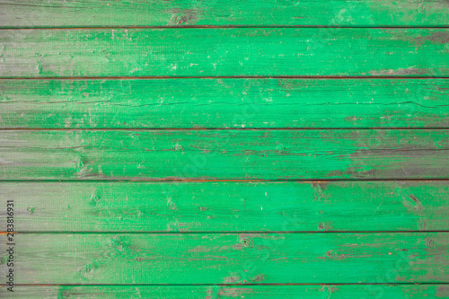 Wooden background texture green paint partly covering planks.