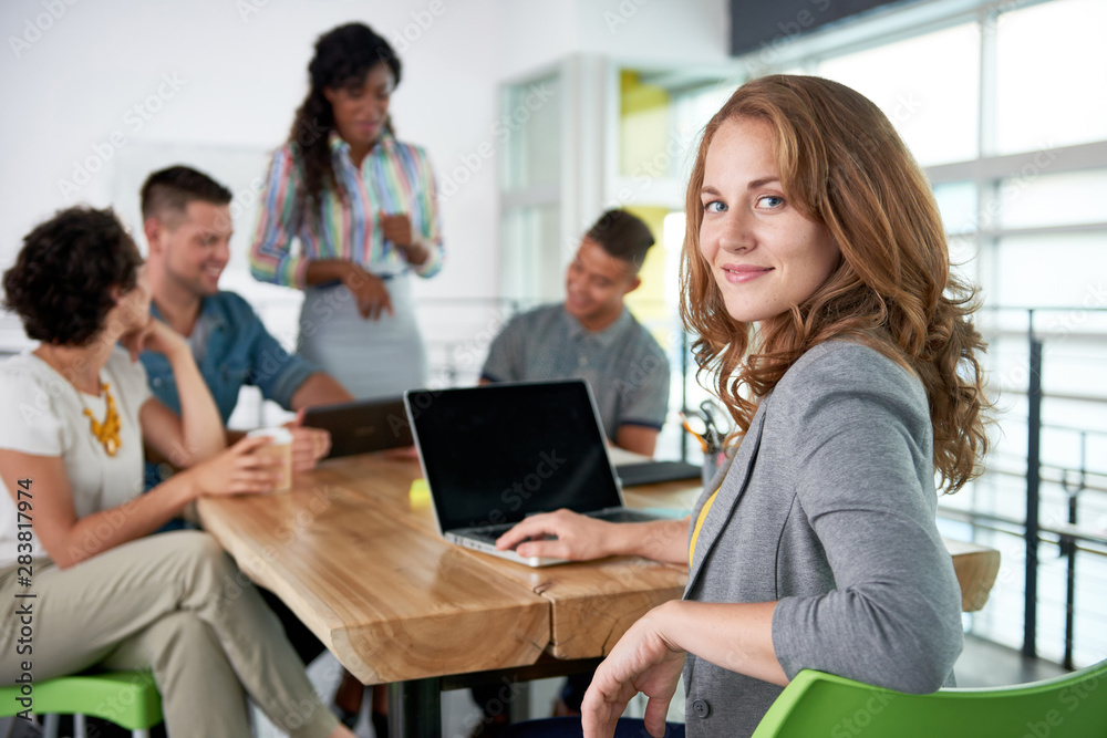 Image of a succesful casual business woman using laptop during meeting