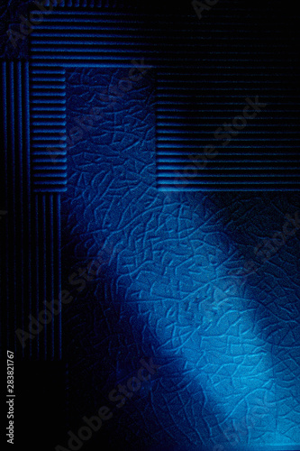 Fototapeta Naklejka Na Ścianę i Meble -  Dark background with a pattern highlighted by a diagonal blue ray of light