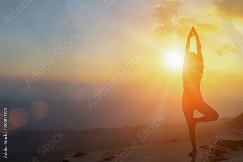Fototapeta Naklejka Na Ścianę i Meble -  Young women meditate while doing yoga meditation, spiritual mental health practice with silhouette of lotus pose having peaceful mind relaxation on mountain outdoor with sunset golden heavenly.