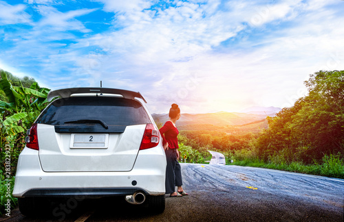 Young beautiful lady standing near broken car for calling for help in the public road