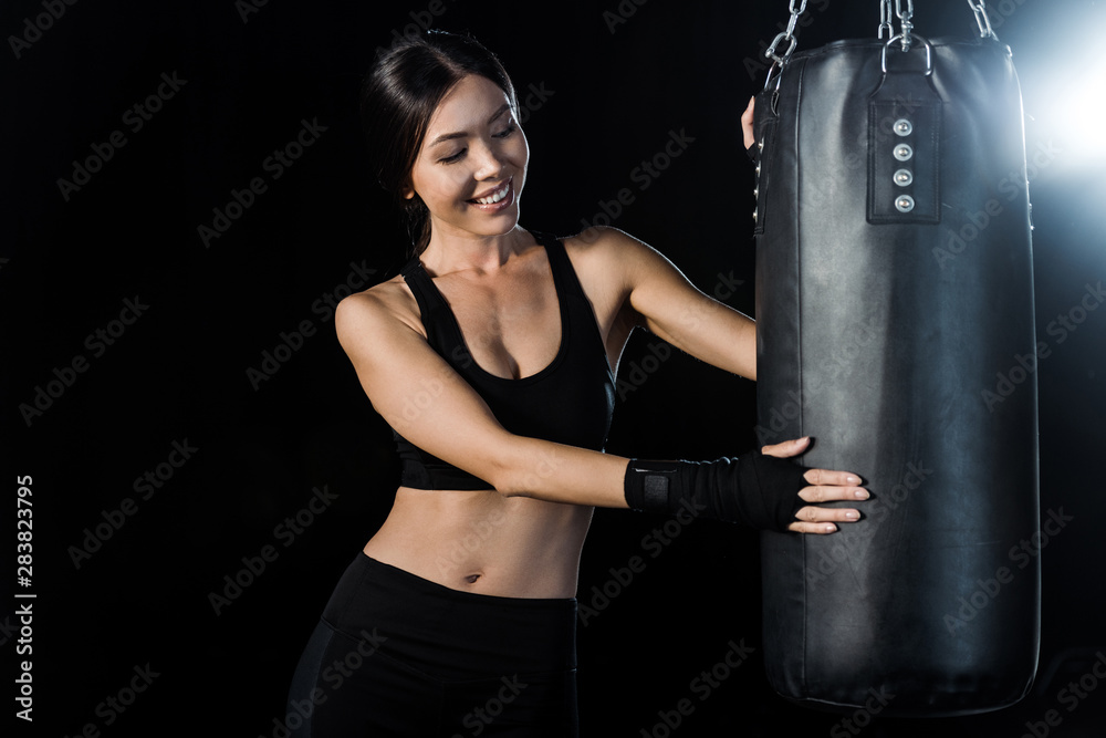 happy girl looking at punching bag isolated on black
