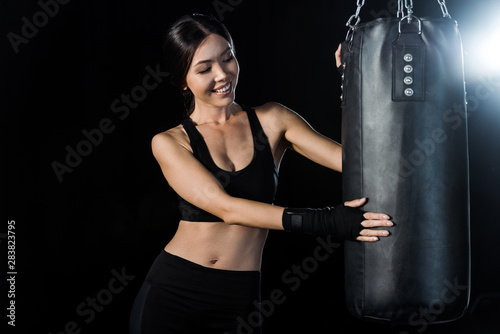 happy girl looking at punching bag isolated on black © LIGHTFIELD STUDIOS
