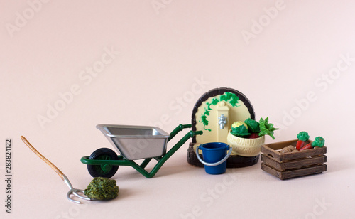 Realistic figures of farm or garden tools: iron wheelbarrow, pitchfork, hay,  blue bucket, watering tap, basket and wooden box of vegetables: potatoes, carrot, cabbage, beet on the light background