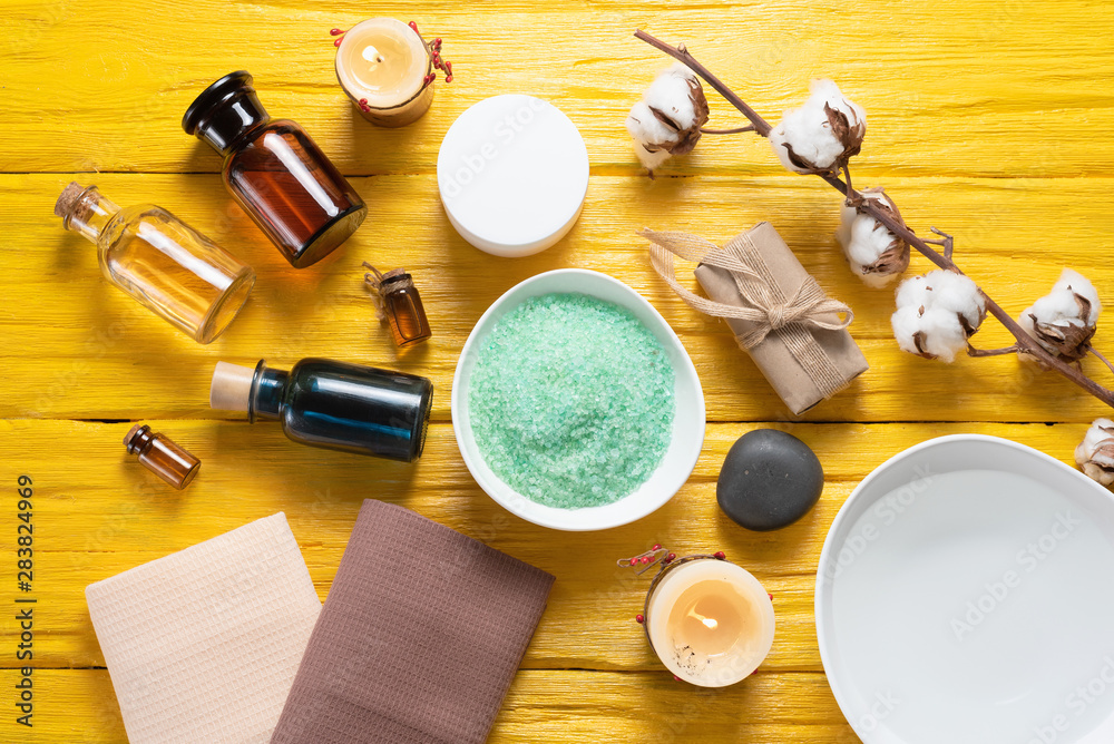 Spa flat lay concept background. Bath salt, aroma oil bottle, soap, towel and a water in bowl on a yellow background. Spa flat lay concept background. Bath salt, aroma oil bottle, soap, towel and a water in bowl on a yellow background.