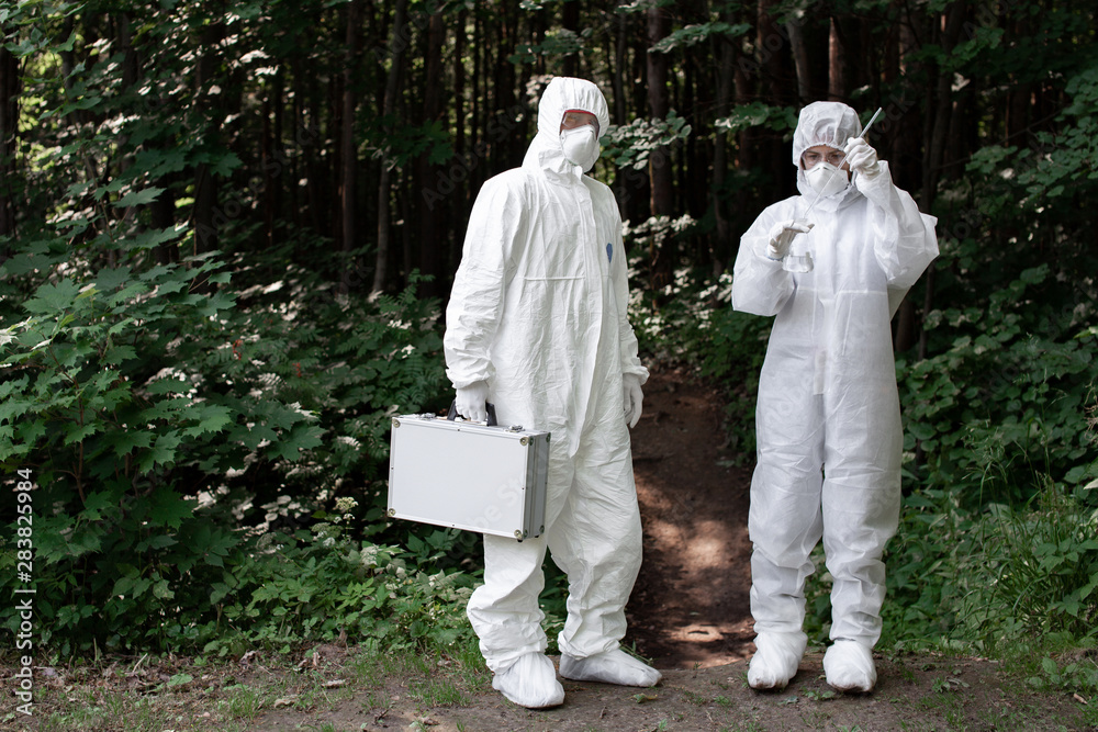 Ecological problem. Pollution. Examine soil. Scientist working in forest in protective mask and suit taking water and soil samples. Chemist makes an analysis of the environment for radiation. 