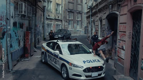 Dangerous police pursuit. Drone view two armed policemen with handguns shouting chasing a criminal drug dealer running away fast in the street. photo