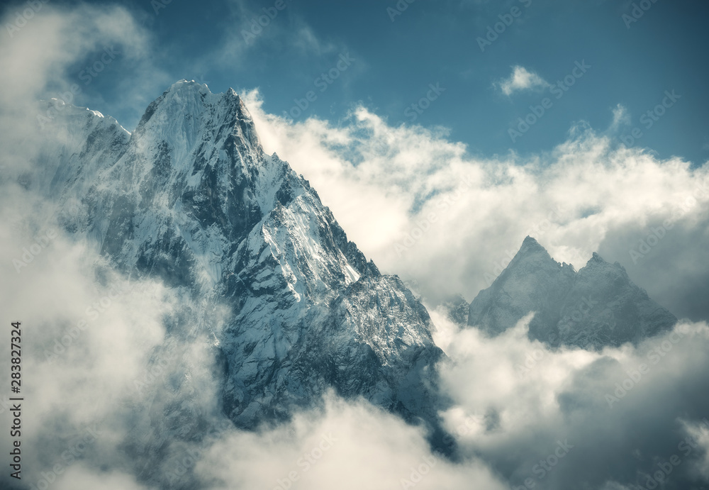 Manaslu mountain with snowy peak in clouds in sunny bright day in Nepal. Landscape with high snow covered rocks and blue cloudy sky. Beautiful nature. Fairy scenery. Aerial view of Himalayan mountains Manaslu mountain with snowy peak in clouds in sunny bright day in Nepal. Landscape with high snow covered rocks and blue cloudy sky. Beautiful nature. Fairy scenery. Aerial view of Himalayan mountains