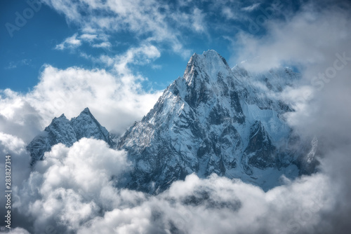 Manaslu mountain with snowy peak in clouds in sunny bright day in Nepal. Landscape with high snow covered rocks and blue cloudy sky. Beautiful nature. Fairy scenery. Aerial view of Himalayan mountains © den-belitsky
